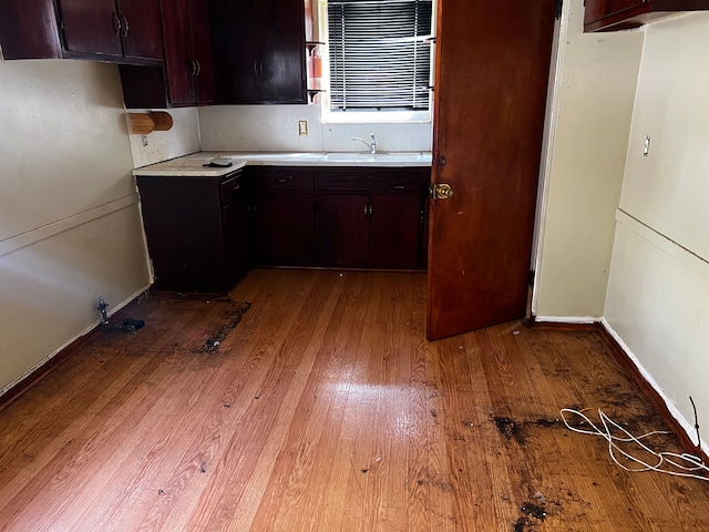 kitchen with light wood-style flooring, light countertops, baseboards, and a sink