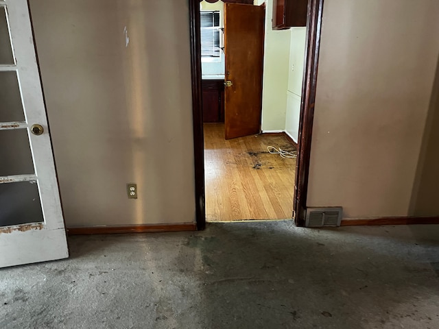 corridor featuring baseboards and concrete flooring