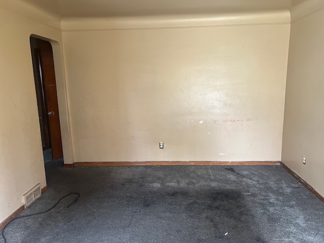 empty room featuring carpet floors, arched walkways, and baseboards