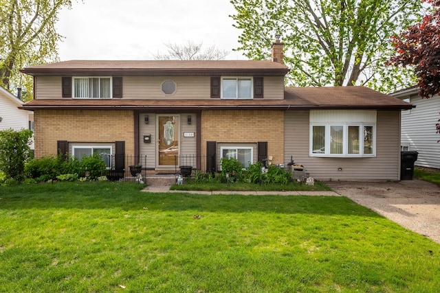 view of front of home featuring a chimney, brick siding, and a front lawn