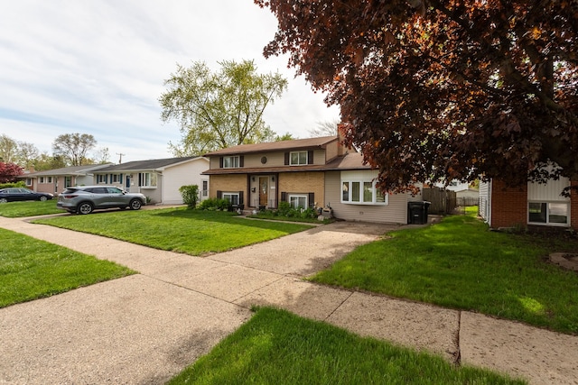 tri-level home featuring brick siding, a front lawn, and driveway