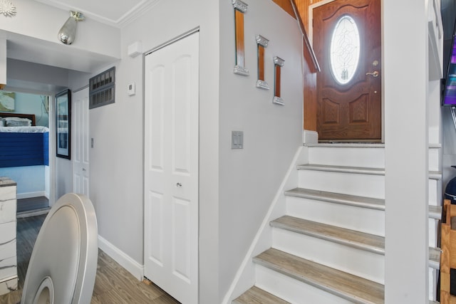 foyer entrance featuring wood finished floors, ornamental molding, baseboards, and stairway