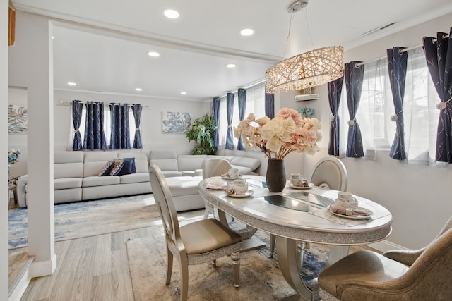 dining area with healthy amount of natural light, crown molding, recessed lighting, and light wood-style flooring