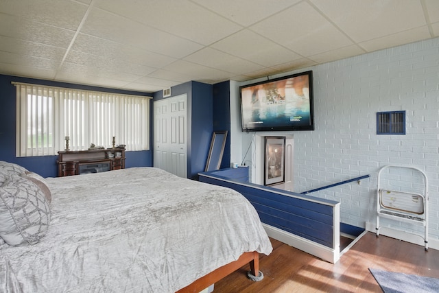 bedroom featuring a paneled ceiling, wood finished floors, and baseboards