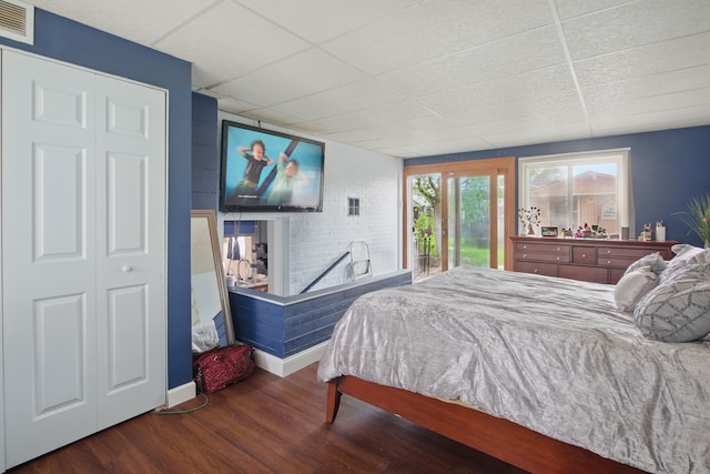 bedroom featuring a drop ceiling, access to outside, wood finished floors, and baseboards