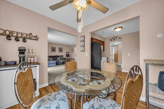 dining space featuring light wood-type flooring, baseboards, and a ceiling fan
