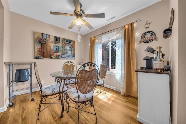 dining area featuring light wood-type flooring, visible vents, baseboards, and a ceiling fan
