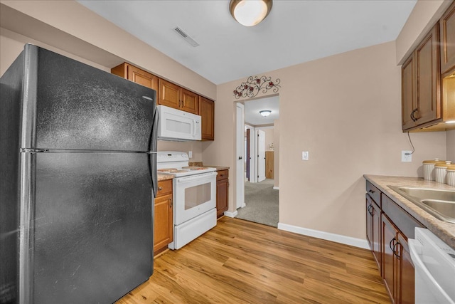 kitchen featuring light wood-style flooring, visible vents, baseboards, white appliances, and light countertops