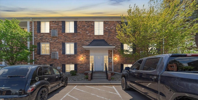 view of property with brick siding and uncovered parking