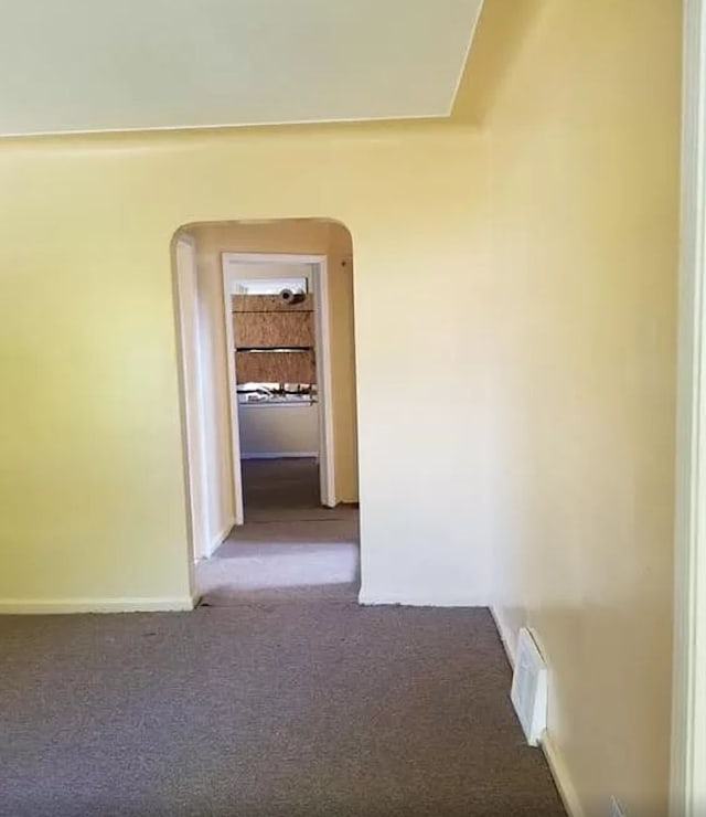 hallway with visible vents, baseboards, arched walkways, and carpet floors