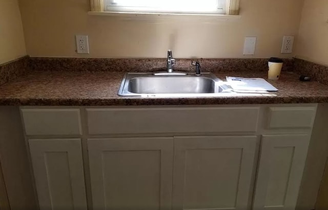 interior details with dark countertops, white cabinetry, and a sink