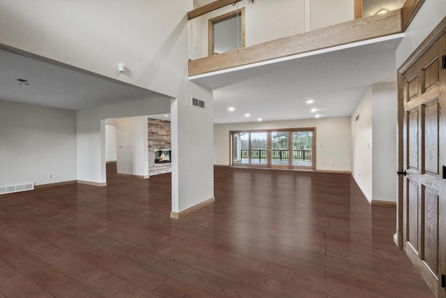 3101 Delano Rd, Oxford, MI 48371 - unfurnished living room featuring a stone fireplace, dark wood finished floors, baseboards, a towering ceiling, and recessed lighting