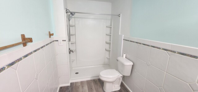 5608 Clifford St, Topinabee, MI 49791 - bathroom with tile walls, wood finished floors, a shower, toilet, and a wainscoted wall