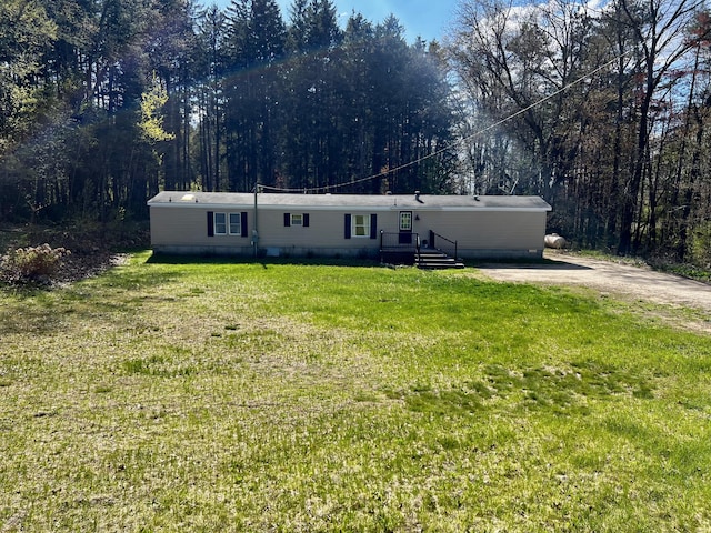 manufactured / mobile home with a front lawn and a forest view
