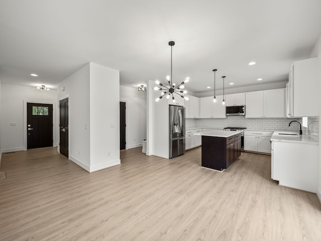 kitchen featuring appliances with stainless steel finishes, a sink, a kitchen island, recessed lighting, and light countertops