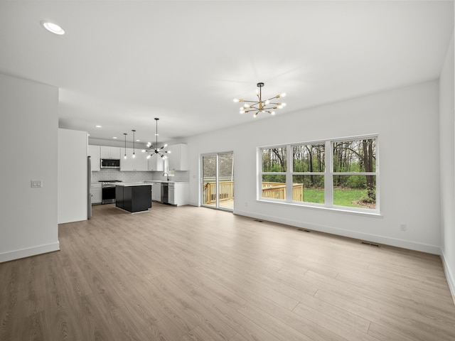 unfurnished living room with a chandelier, recessed lighting, baseboards, and light wood-type flooring