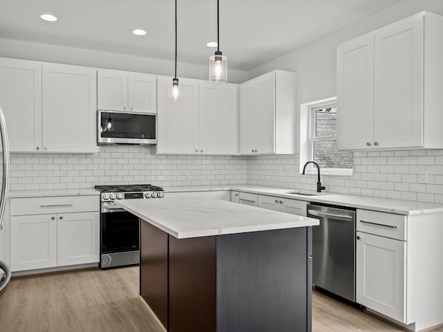 kitchen with stainless steel appliances, a sink, light wood-type flooring, white cabinets, and recessed lighting