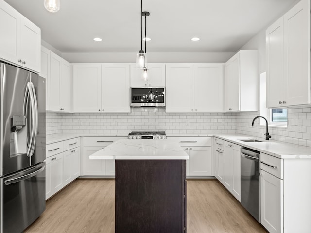 kitchen with appliances with stainless steel finishes, a sink, light wood finished floors, white cabinetry, and recessed lighting