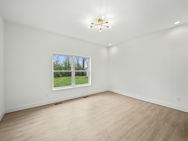spare room featuring a chandelier, light wood-style floors, baseboards, and recessed lighting