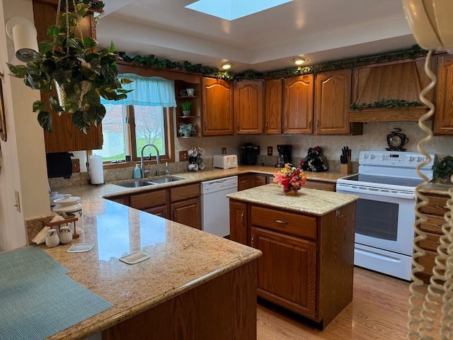 275 Madison St, Port Austin, MI 48467 - kitchen with light wood finished floors, a sink, brown cabinetry, a skylight, and white appliances