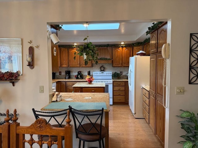 275 Madison St, Port Austin, MI 48467 - kitchen featuring a peninsula, brown cabinetry, white appliances, light wood-style flooring, and light countertops