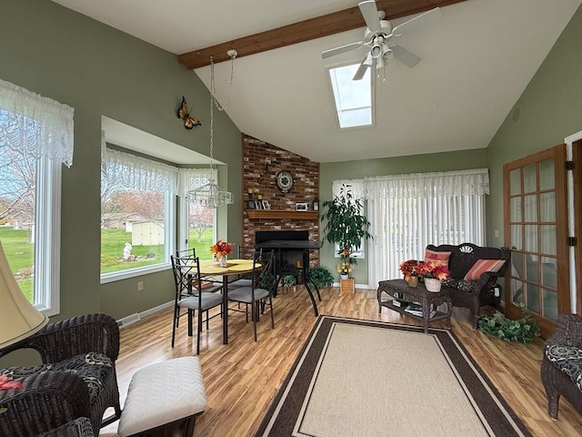 275 Madison St, Port Austin, MI 48467 - living area with baseboards, lofted ceiling with skylight, ceiling fan, wood finished floors, and a fireplace