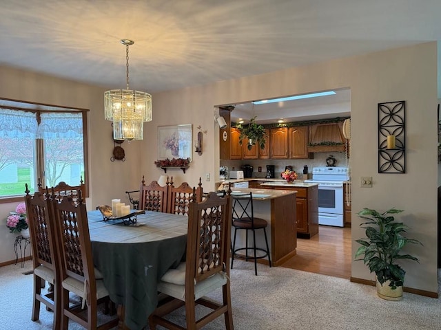 275 Madison St, Port Austin, MI 48467 - dining space featuring light colored carpet, a chandelier, and baseboards