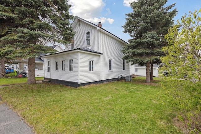 view of side of home with a yard and a chimney