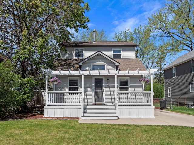 traditional-style house with a porch, a shingled roof, and a front lawn