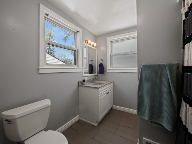 bathroom featuring toilet, baseboards, and vanity