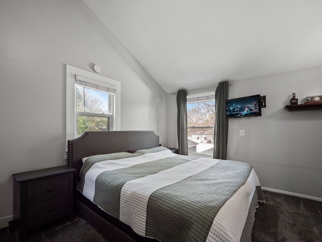 bedroom with vaulted ceiling, dark colored carpet, and baseboards