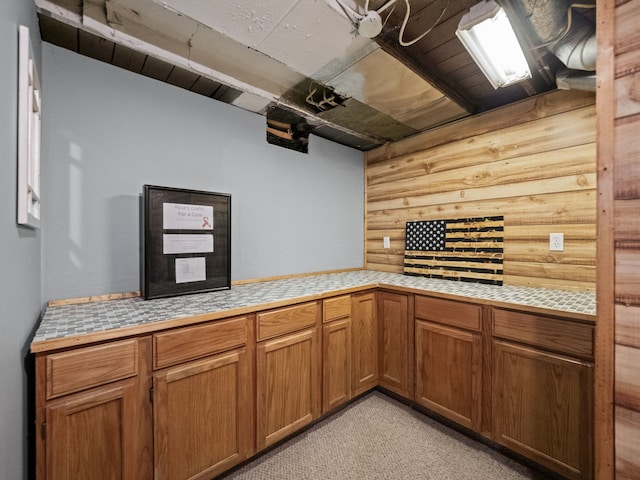 kitchen with brown cabinetry, light carpet, and tile countertops