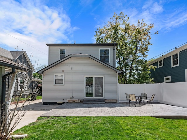 rear view of property featuring a patio area, fence, and a lawn
