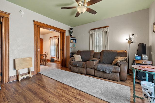 living area featuring ceiling fan, baseboards, and dark wood-type flooring