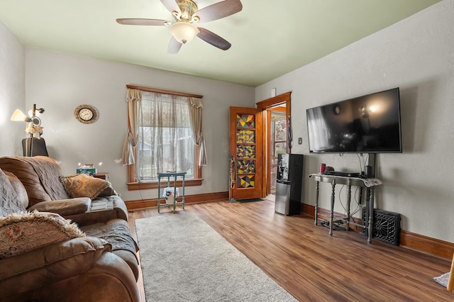 living area featuring ceiling fan, baseboards, and wood finished floors