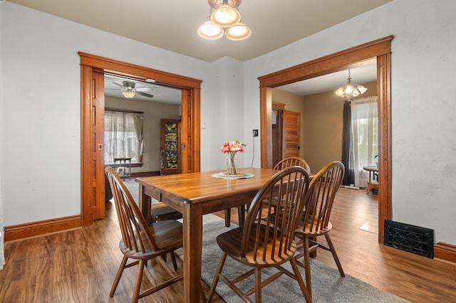 dining room featuring an inviting chandelier, visible vents, wood finished floors, and baseboards
