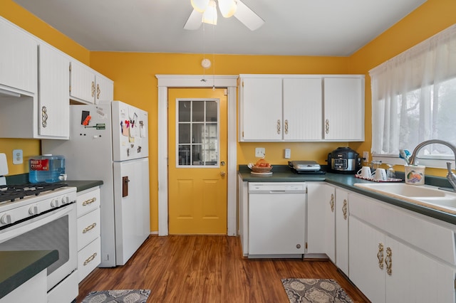 kitchen with a ceiling fan, a sink, white cabinets, dark wood finished floors, and white appliances