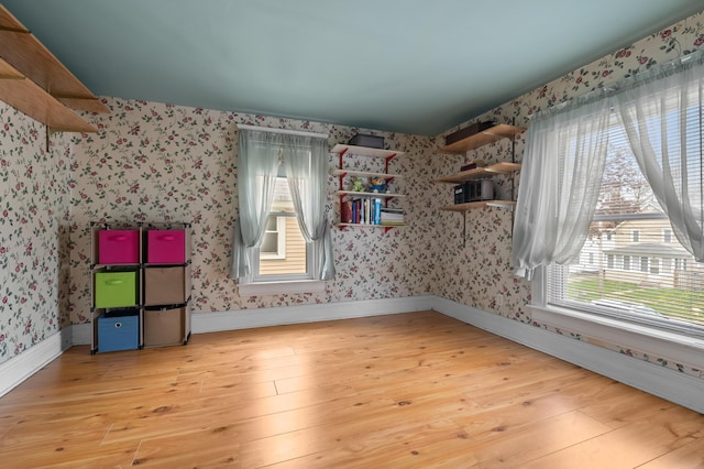 additional living space featuring wallpapered walls, light wood-style floors, and baseboards
