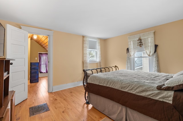 bedroom featuring light wood finished floors, visible vents, and baseboards