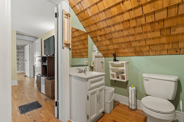 bathroom with lofted ceiling, baseboards, visible vents, and wood finished floors