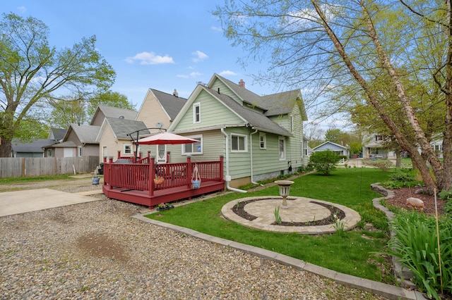 back of house with a yard, a chimney, fence, a wooden deck, and roof with shingles