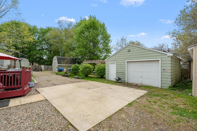 detached garage with fence and concrete driveway