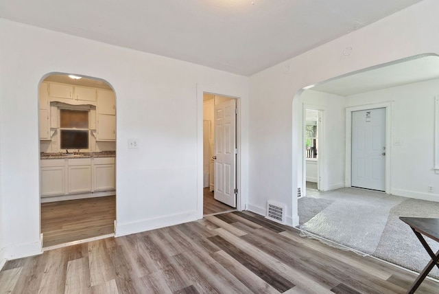 5011 Baldwin Blvd, Flint, MI 48505 - unfurnished living room featuring arched walkways, baseboards, light wood-style flooring, and visible vents