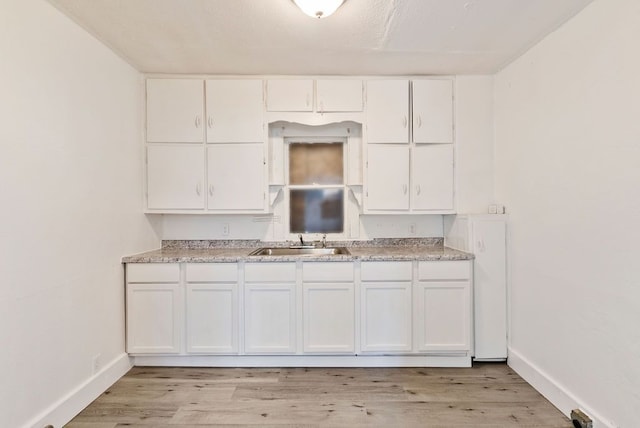 5011 Baldwin Blvd, Flint, MI 48505 - kitchen with a sink, light wood-type flooring, white cabinetry, light countertops, and baseboards