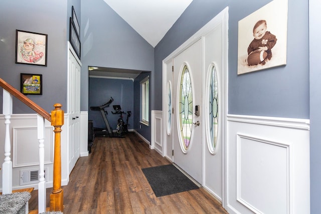 foyer entrance featuring stairs, a decorative wall, visible vents, vaulted ceiling, and dark wood-style floors