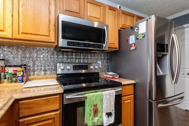 kitchen featuring light countertops, stainless steel appliances, crown molding, and decorative backsplash