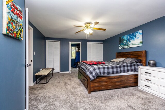 bedroom with a ceiling fan, carpet floors, baseboards, and multiple closets
