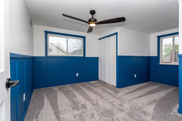unfurnished bedroom with wainscoting, carpet floors, and a decorative wall