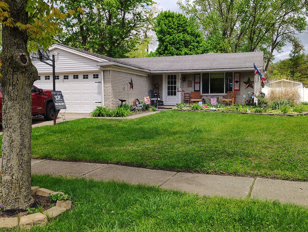 single story home with brick siding, an attached garage, a front yard, and a porch
