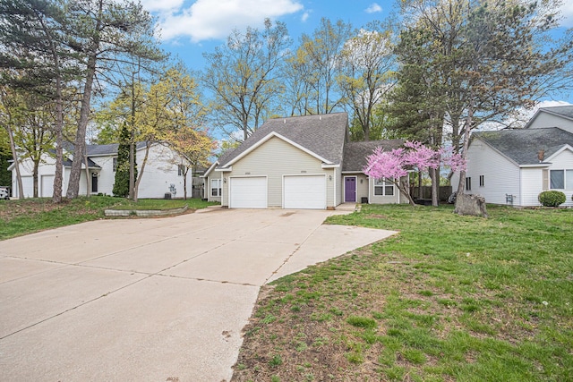 view of front of home with an attached garage, roof with shingles, driveway, and a front lawn